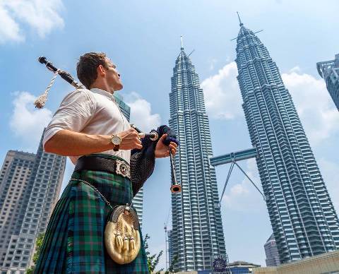 Escocês com gaita de fole em frente Petronas Twin Towers na Malásia